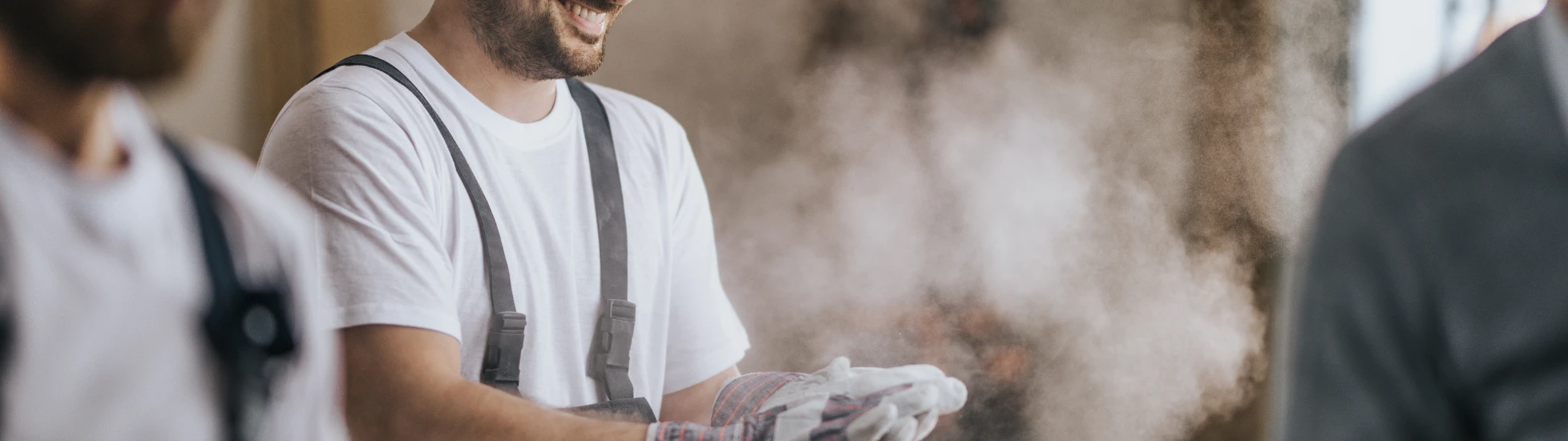 Happy construction worker with dusty gloves