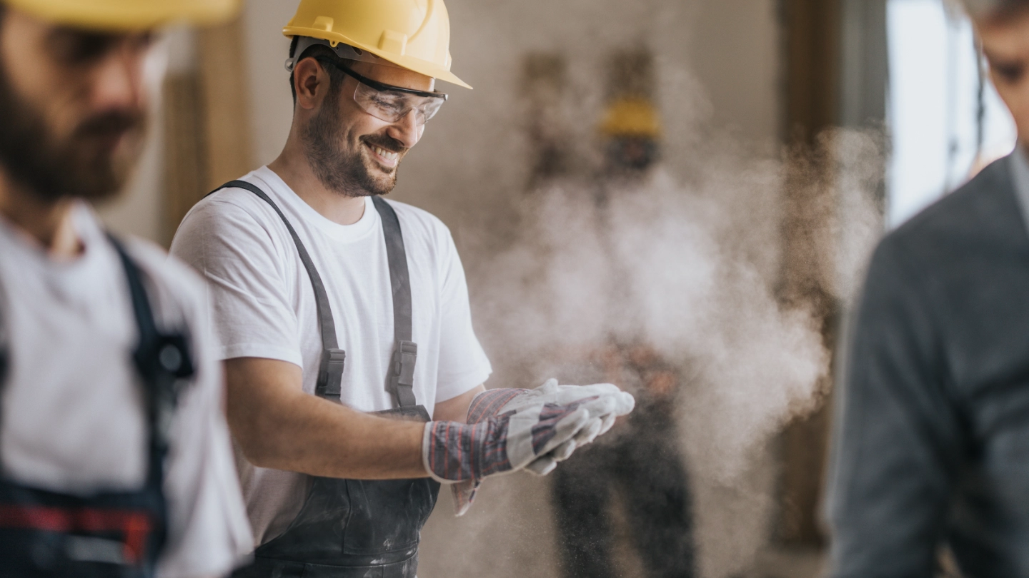 Happy construction worker with dusty gloves Happy construction worker with dusty gloves